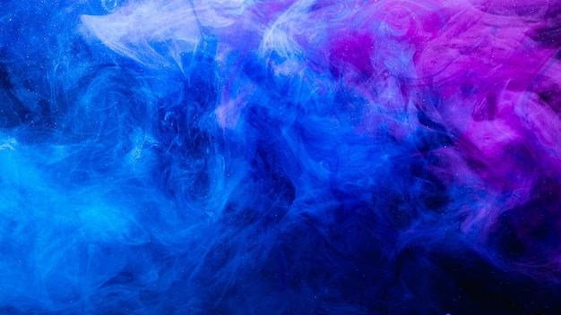 Colore in acqua. Sfondo artistico. Trama di vapore incandescente fluorescente. Nuvola di fumo glitter viola blu ultravioletto brillante si fondono su scuro.