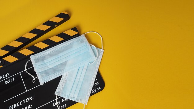 Colore nero e giallo Clapper board o ardesia di film con maschera facciale. utilizza nella produzione video e nell'industria cinematografica su sfondo giallo.