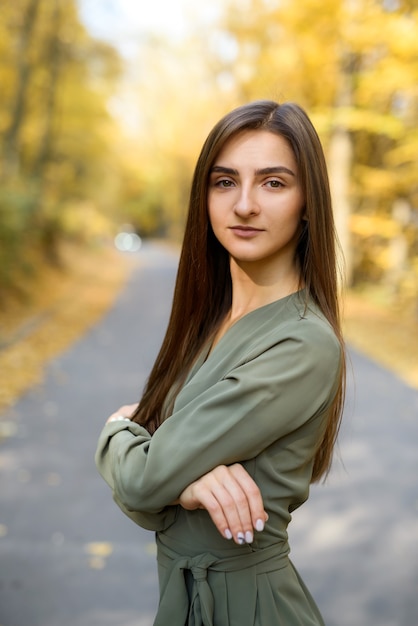 Colori autunnali. Bella donna in cappotto in posa nella foresta sul ciglio della strada