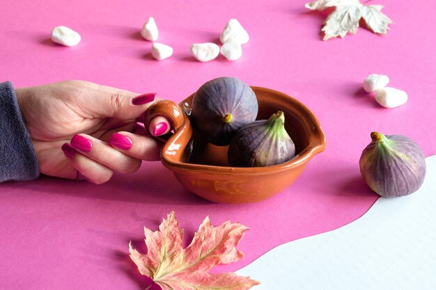 Colori autunnali Frutti di fico viola e magenta in una ciotola di terracotta in mano