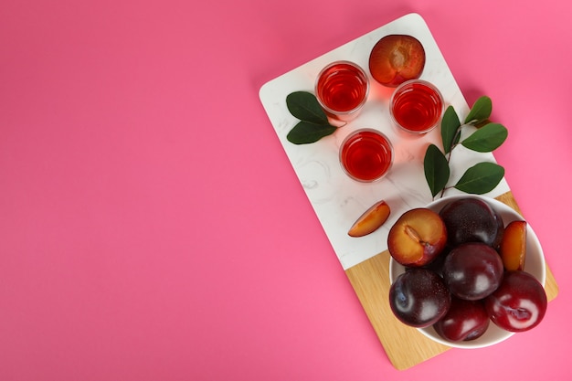 Colpi di brandy di prugne e ingredienti su sfondo rosa