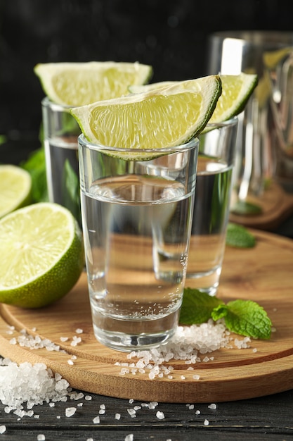 Colpi di tequila con fette di lime, sale e menta su legno