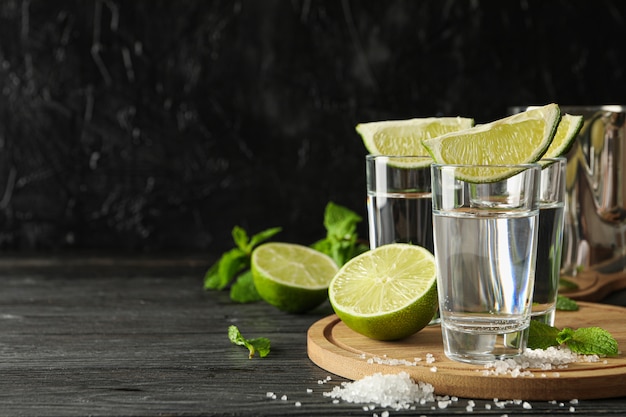 Colpi di tequila con fette di lime, sale e menta su legno