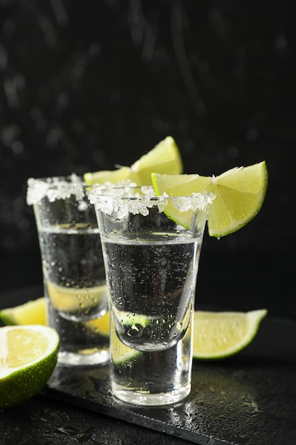 Colpi di tequila con fette di sale e lime su nero bagnato