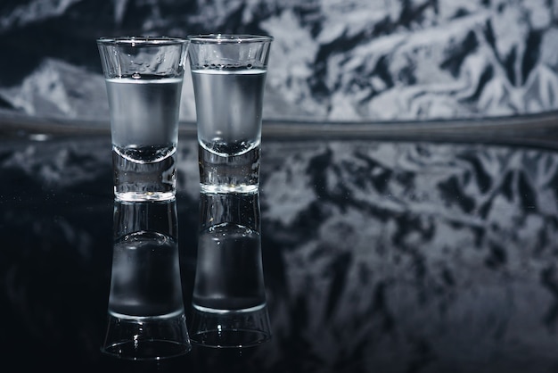 Colpi di vodka con ghiaccio sul tavolo nero, copia spazio