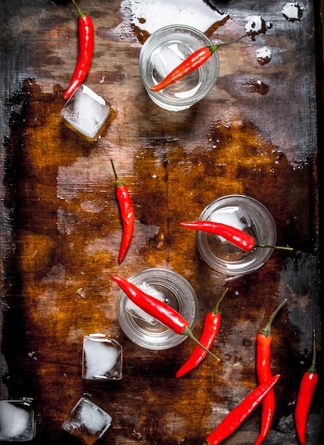 Colpi di vodka con peperoncino su un tavolo di legno.