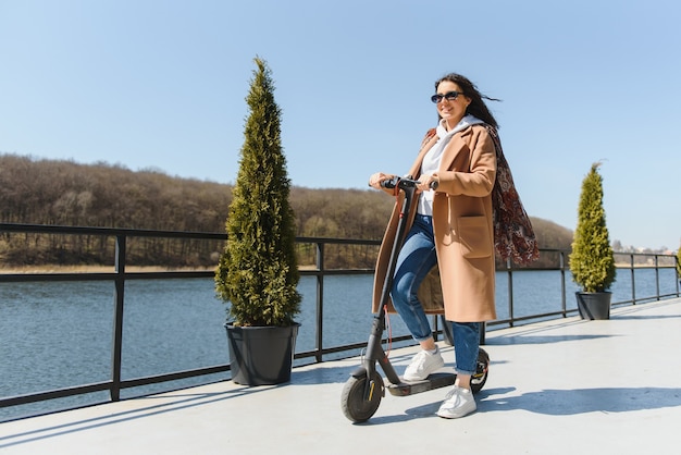 Colpo a figura intera donna in sella a uno scooter elettrico, generazione moderna