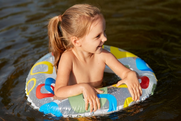 Colpo all'aperto di bella bambina allegra che gioca in acqua