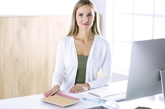 Colpo alla testa della donna d'affari mentre si lavora con il computer alla scrivania in un ufficio moderno. Designer o avvocato donna sembra bella in abiti casual bianchi. Concetto di uomini d'affari.