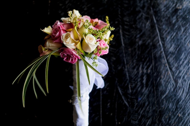 Colpo del primo piano del bouquet da sposa di una bella sposa con delicati fiori di rosa