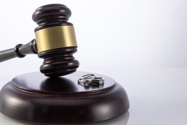 Colpo del primo piano del martelletto del giudice con gli anelli di nozze - concetto di divorzio