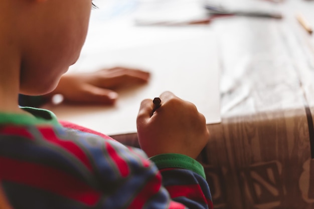 Colpo del primo piano dell'angolo alto di un bambino che disegna con una matita