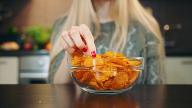 Colpo del primo piano della donna che mangia le patatine fritte.