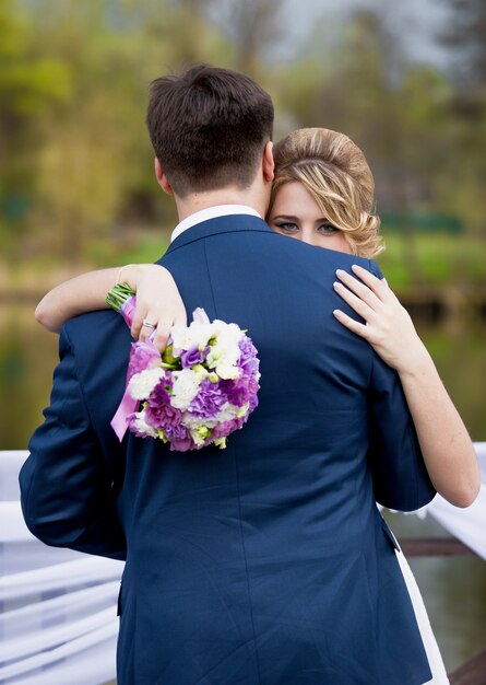 Colpo del primo piano della sposa bionda elegante che guarda sopra la spalla dello sposo