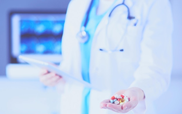 Colpo del primo piano delle mani del medico che tengono pillole e tablet in clinica