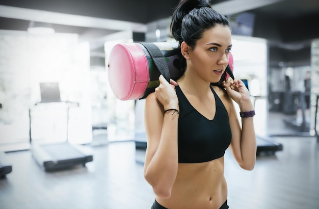 Colpo del primo piano di donna sportiva bruna che si allena con il sacchetto di sabbia mentre si fa esercizio per le gambe di testa nel fitness club o in palestra Attraente donna atletica che fa duro allenamento con allenamento con i pesi con spazio per la copia