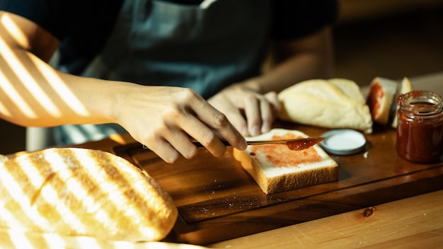 Colpo del primo piano di marmellata di lamponi diffusione irriconoscibile sulla fetta di pane con coltello da tavola sul tagliere