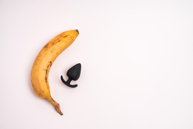 Colpo del primo piano di una banana e un plug anale isolato su uno sfondo bianco