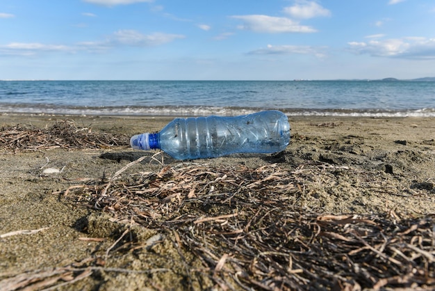 Colpo del primo piano di una bottiglia di plastica su una spiaggia sabbiosa