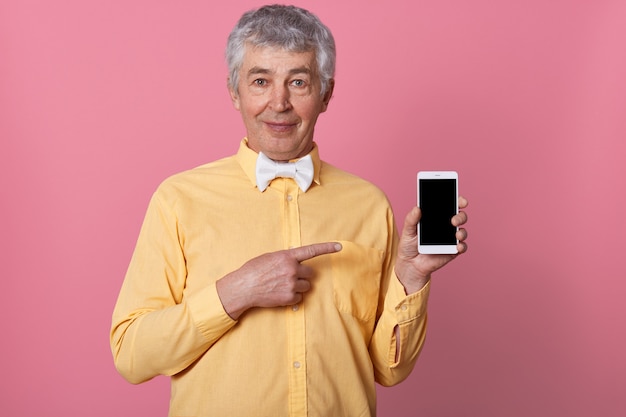 Colpo dell'interno dell'uomo dai capelli grigi maturo in camicia gialla con farfallino