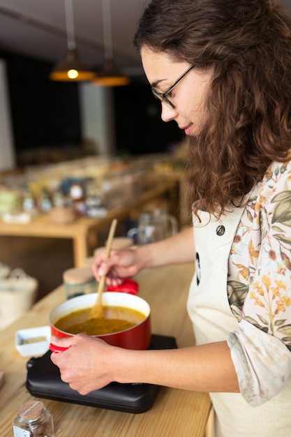 Colpo di bella giovane donna che cucina in negozio biologico.