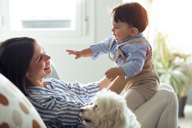 Colpo di bella giovane madre con il suo bambino che gioca e ama nel soggiorno di casa.