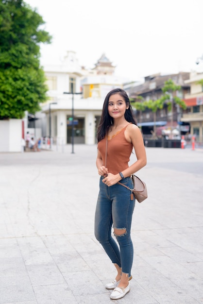 Colpo di corpo pieno di giovane bella donna asiatica che pensa nelle strade all'aperto