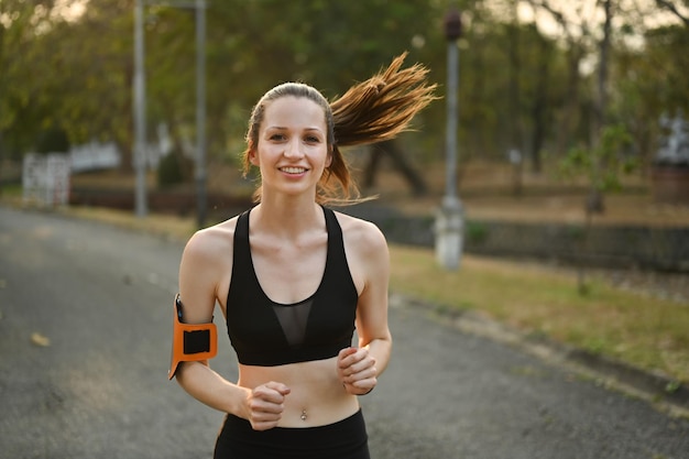 Colpo di felice donna atletica che fa jogging al parco alla luce dell'alba Fitness sport e concetto di stile di vita sano