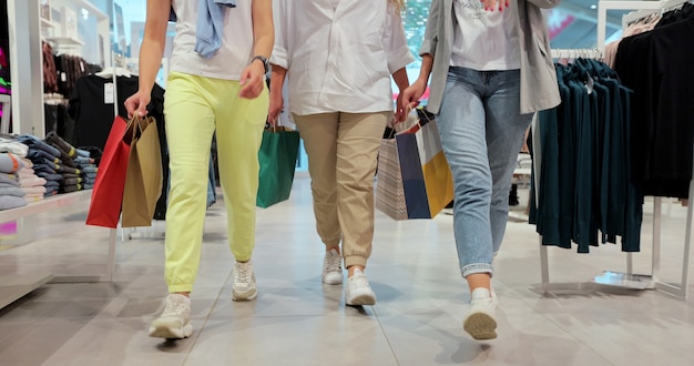 Colpo di gambe femminili che camminano attraverso un centro commerciale in abiti colorati. Stile di vita giovanile, amicizia e concetto di consumismo. La spesa dopo la quarantena.
