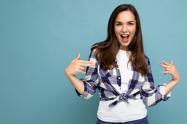 Colpo di giovane bella donna castana gioiosa divertente positiva con emozioni sincere che indossa camicia a quadri alla moda