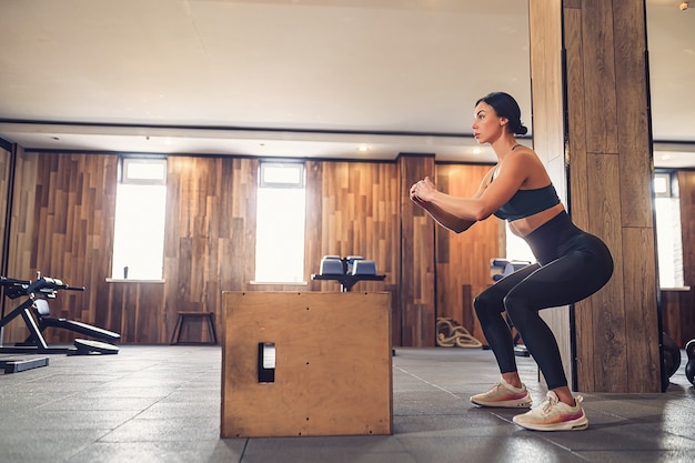 Colpo di giovane donna che lavora con una scatola in palestra