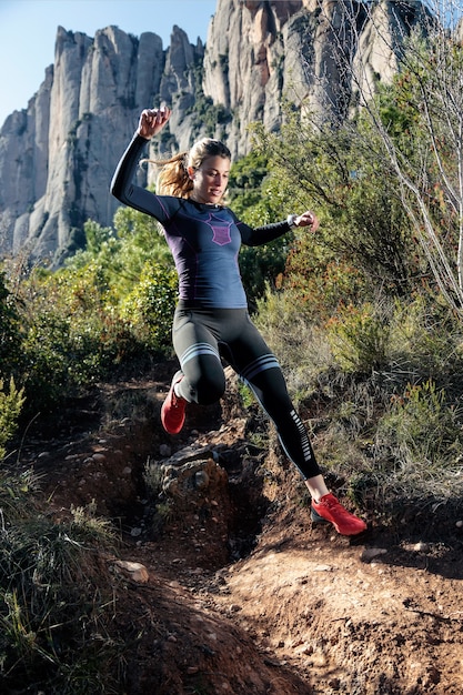 Colpo di giovane donna fitness trail runner correre e saltare sulla montagna rocciosa.