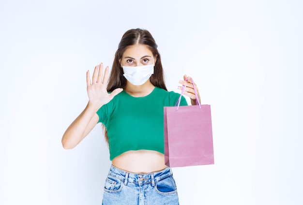 Colpo di giovane donna in maschera medica che tiene borsa viola.