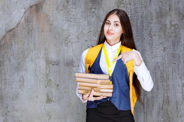 Colpo di studentessa dai capelli lunghi con libri in piedi. Foto di alta qualità