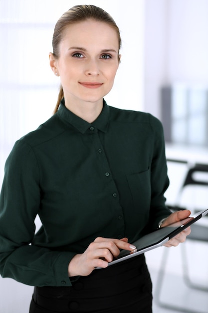 Colpo di testa della donna d'affari in un ufficio moderno Segretario o avvocato donna che utilizza un computer tablet mentre si sta in piedi Concetto di uomini d'affari