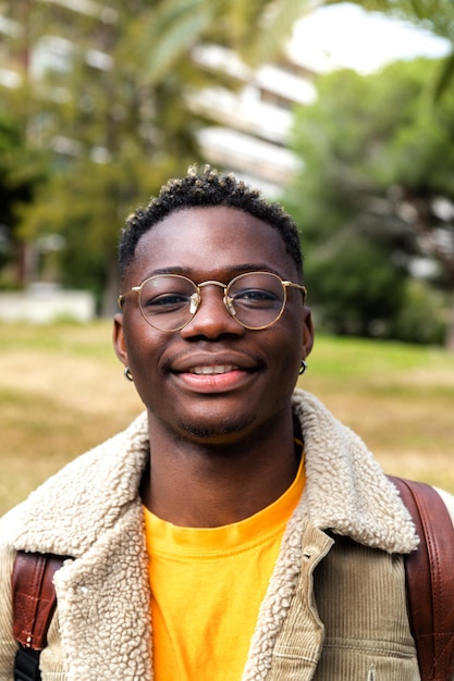 Colpo di testa di sorridente fiducioso studente di college adolescente afroamericano con occhiali guardando la fotocamera Immagine verticale Concetto di educazione