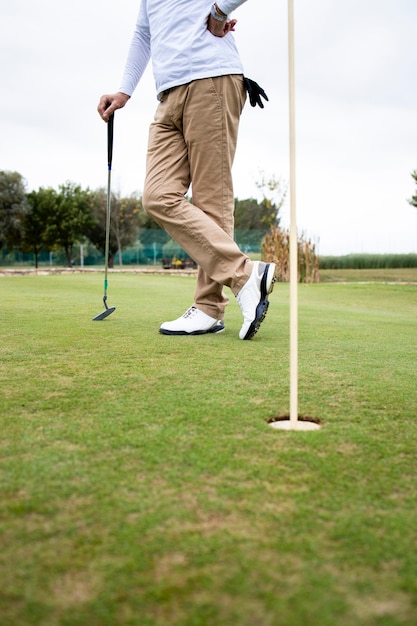 Colpo di un irriconoscibile giocatore di golf in piedi sul campo da golf.