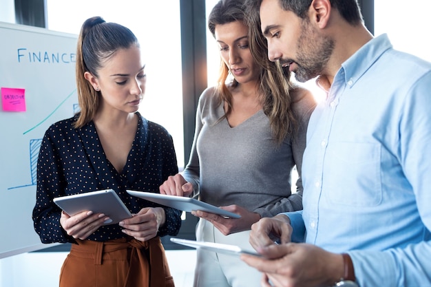 Colpo di uomini d'affari che lavorano con tablet digitale mentre discutono insieme nella sala conferenze in ufficio.