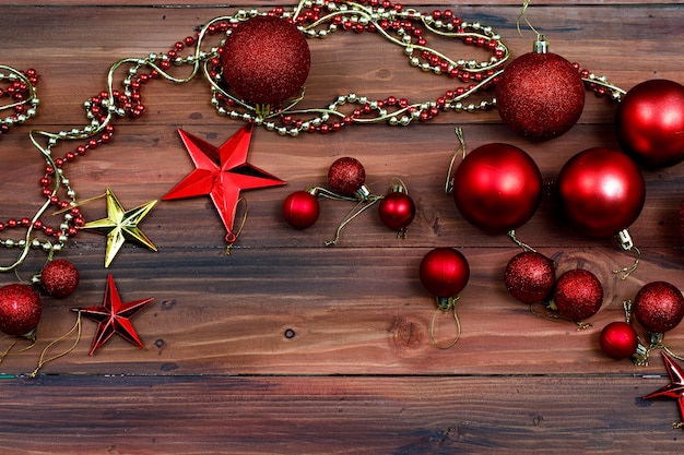 Colpo di vista dall'alto della festa di Natale e felice anno nuovo elementi decorativi rosso lucido decorazioni palle catena di perline d'argento lampadina e stella lucida dorata posizionata sul vecchio tavolo di legno scuro con lo spazio della copia.