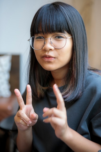 Colpo in testa del ritratto dell'adolescente asiatico che fa i segni di pace