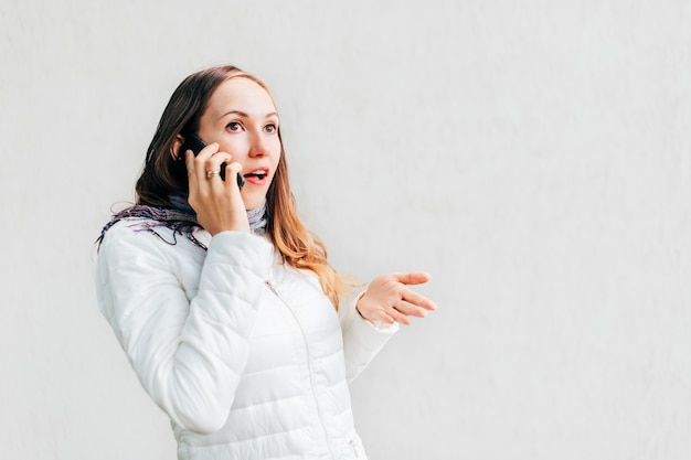 Colpo in testa del ritratto di giovane donna caucasica gesticolano entusiasta discutendo sul telefono cellulare.