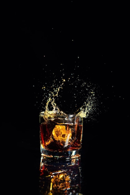 Colpo isolato di whisky con spruzzata su sfondo nero