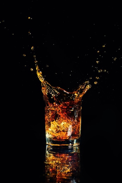Colpo isolato di whisky con spruzzata su sfondo nero