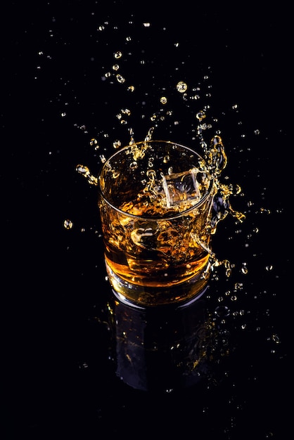 Colpo isolato di whisky con spruzzata su sfondo nero