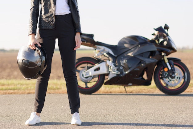 Colpo orizzontale ritagliato di motociclista femmina vestita in giacca di pelle nera