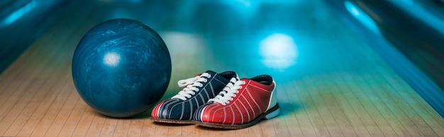 Colpo panoramico di scarpe da bowling e palla sulla pista da bowling nel club di bowling