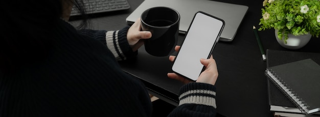 Colpo potato della donna di affari che si rilassa con il caffè e lo smartphone caldi