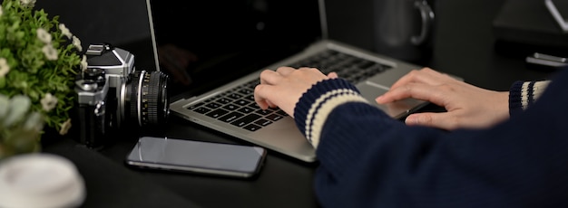 Colpo potato delle free lance femminili che lavorano con il computer portatile sulla tavola nera