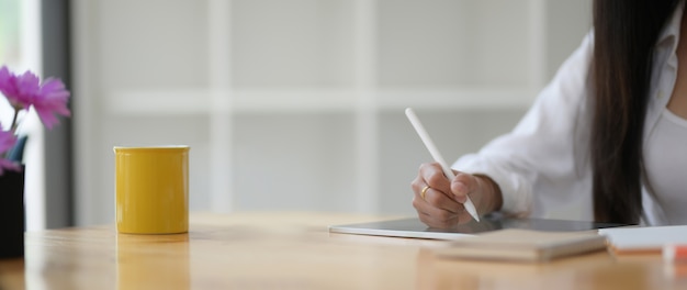 Colpo potato di giovane scrittura dello studente di college sulla compressa digitale con lo stilo