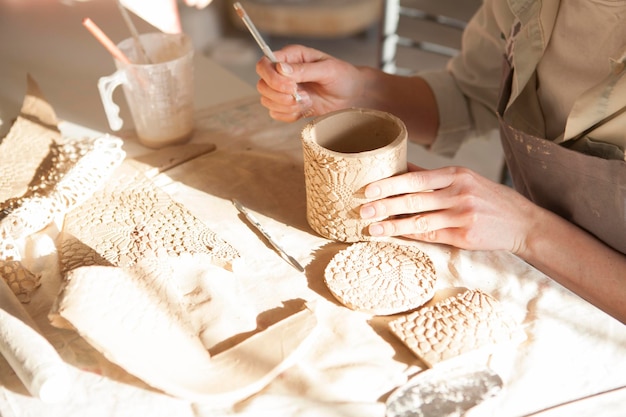 Colpo ritagliato di donna irriconoscibile che fa una tazza a lezione di ceramica, spazio di copia